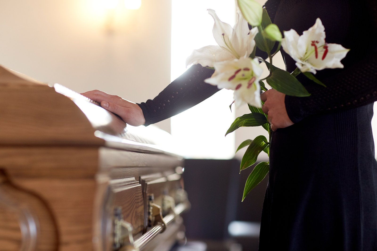 A Mourner Touches the Casket of a Loved One